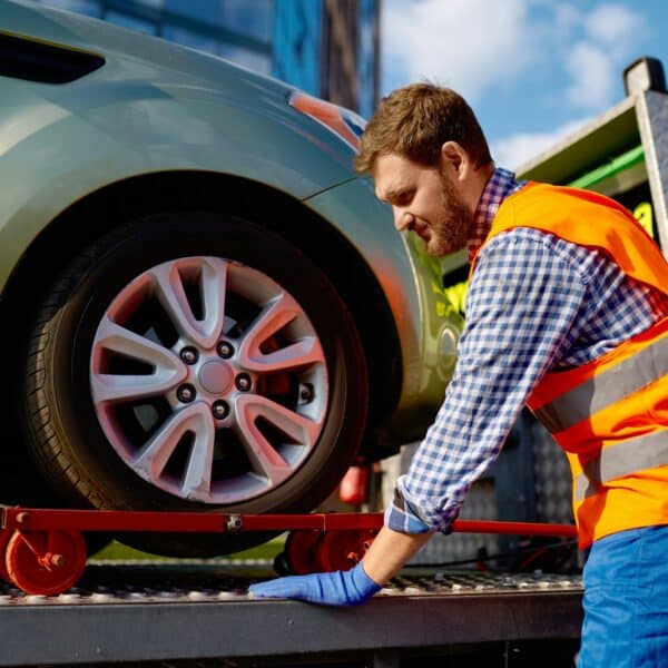 Tow truck operator fixing the car on platform
